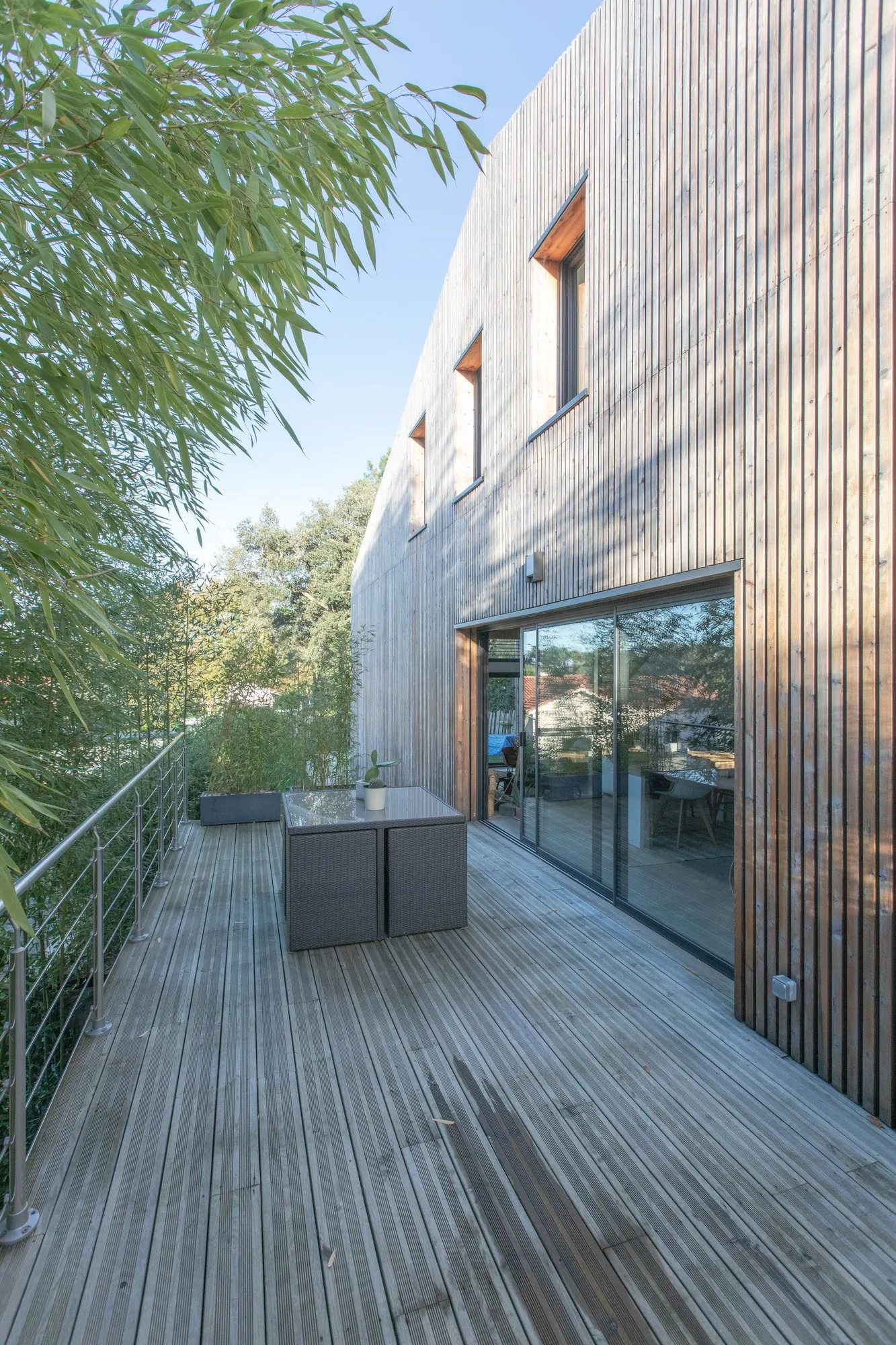 La terrasse en bois le long de la façade en mélèze, à l’étage